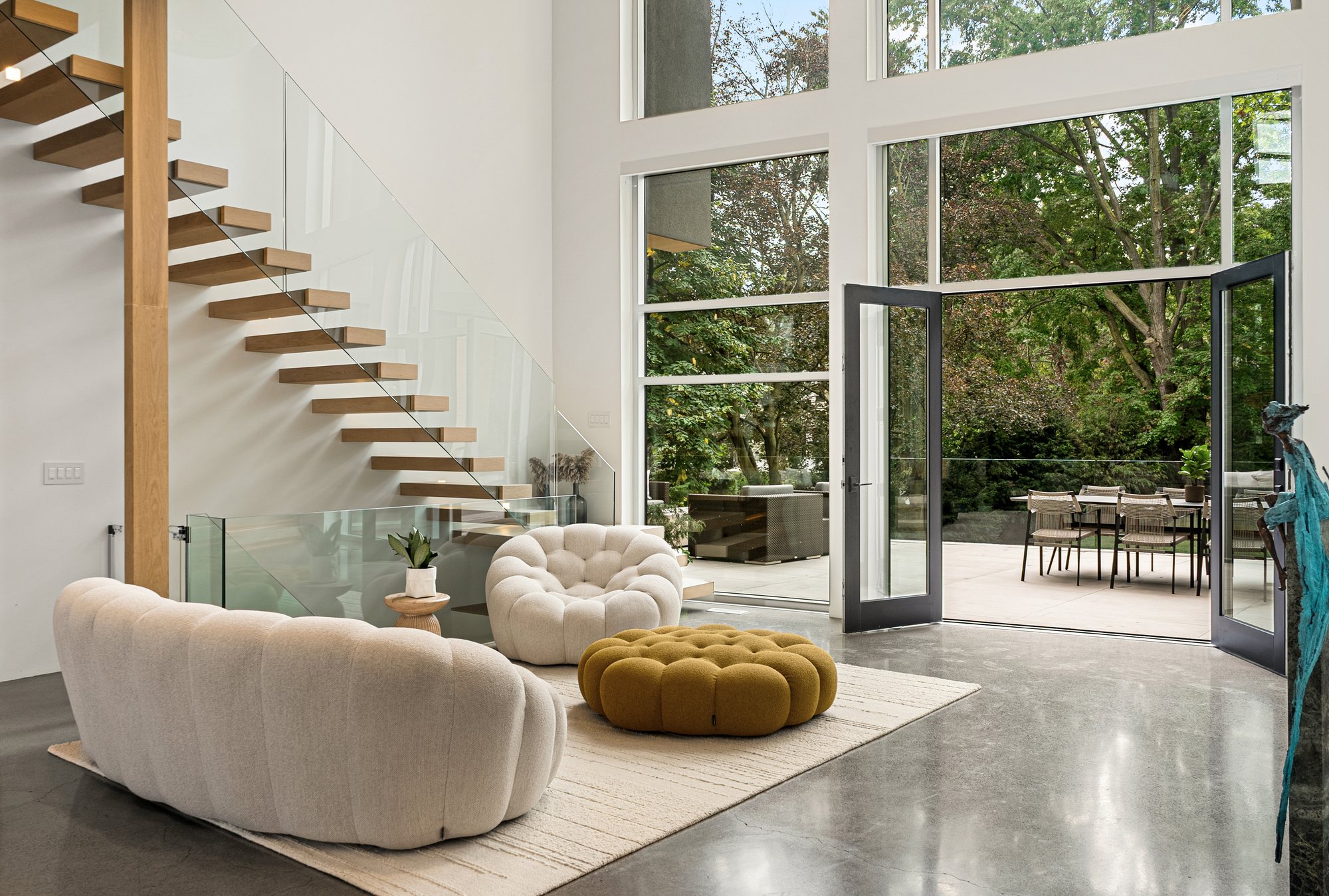 Double-height living room with curved seating and a glass staircase